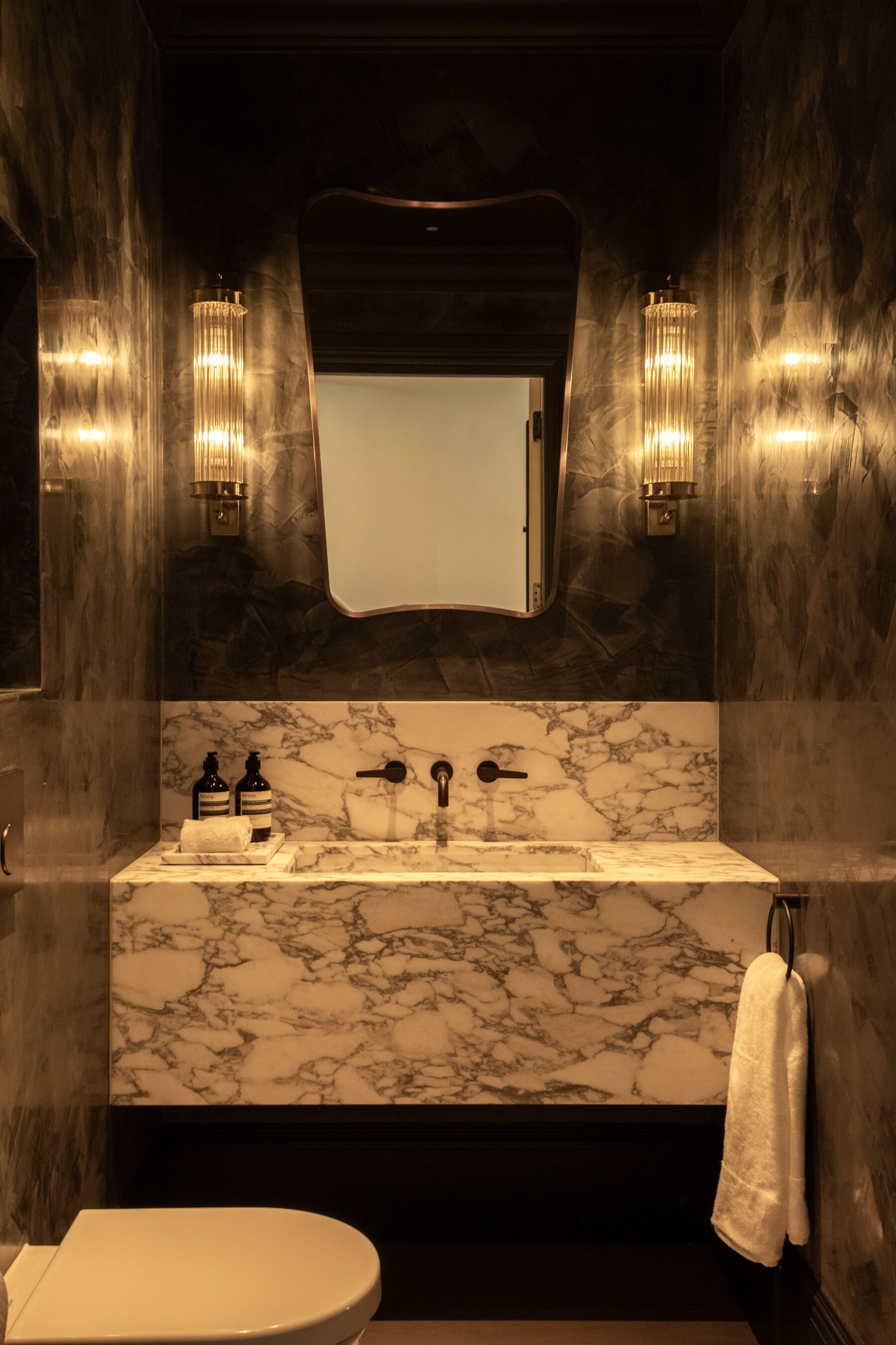 Powder room with marble vanity and polished plaster walls